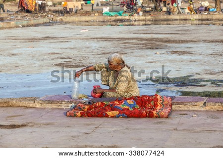 DELHI, INDIA - NOV 17, 2011: old poor woman rests with a bottle of water at empty  Meena Bazaar in Delhi, India. Shah Jahan founded the bazaar in the 17th century inspired by the islamic architecture.