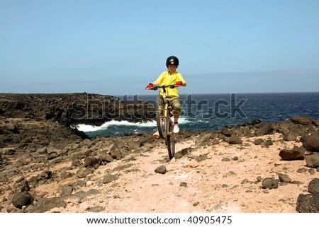 child is doing tricks with its mountain bike in the outback at the cost side