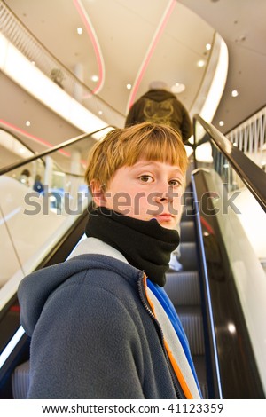 child on moving staircase looks self confident and smiles