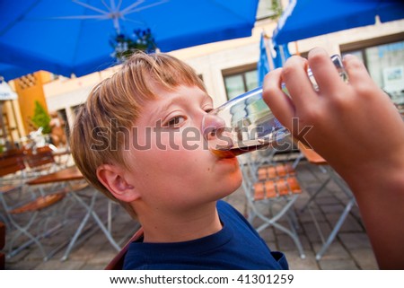 happy child drinks non alcoholic drinks out of a beer glass and enjoys the drink with a slice of lemon