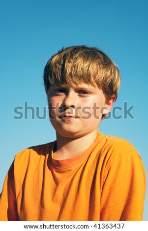 child boy in orange T-shirt  is looking self confident and happy after doing sports