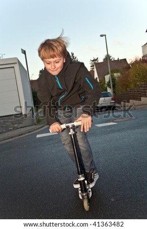 child, boy is doing tricks, jumping with a scooter on the street and having fun and enjoying it