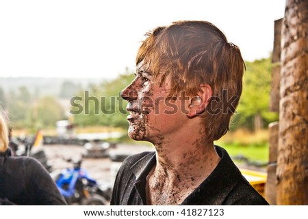 young boy is fascinated by quad driving and enjoys is, his face is dirty from mud