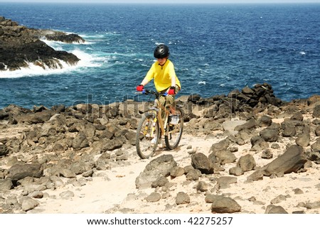 boy rides with his mountain bike along a rough area at the costline in lanzarote