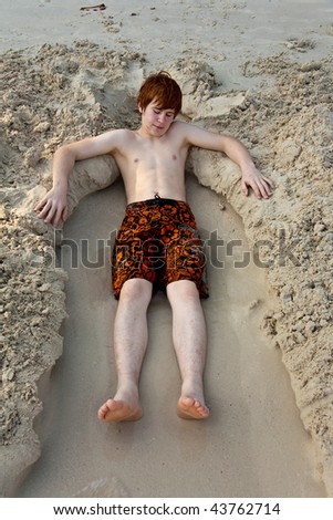 young boys is enjoying playing at the beach and building figures out of sand at the beautiful white beach