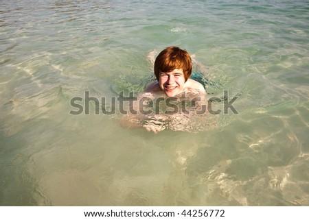 boy with red hair is swimming  in the  beautiful sea with crystal clear water and blue sky and enjoying the water