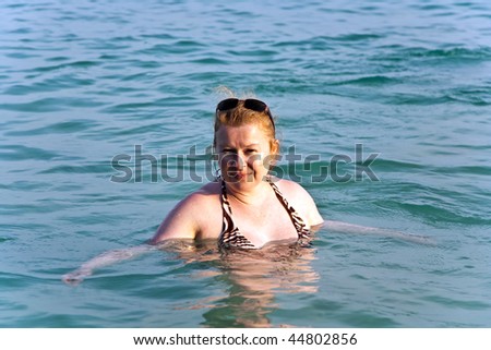 happy woman with red hair enjoys the clear warm salt water in the sea