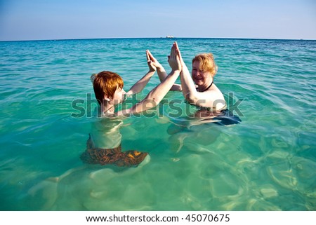 red haired woman and son are enjoying the beautiful clean sea and having fun