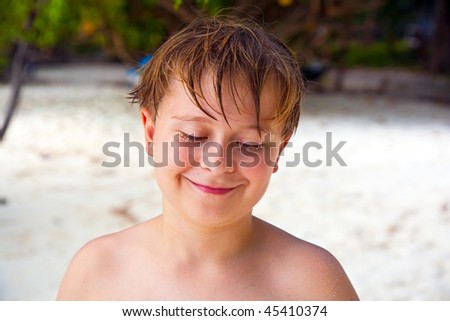 happy boy with wet hair at the beach smiles and looks very self confident