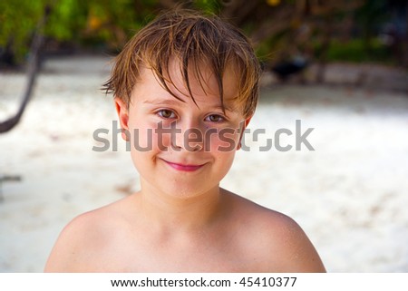 happy boy with wet hair at the beach smiles and looks very self confident