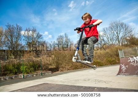 boy jumping with a scooter over a funbox