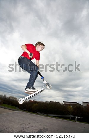 Boy riding a scooter going airborne at a scooter park