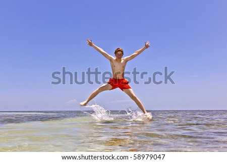 boy makes athletic jumps in the crystal clear water