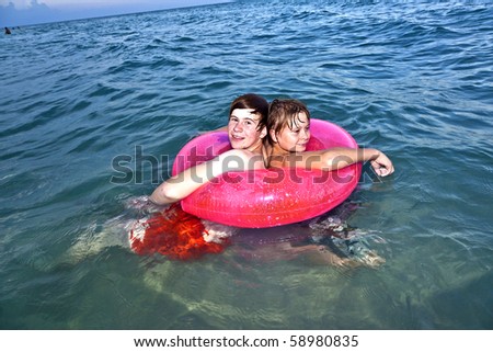two brothers in a swim ring have fun in the ocean