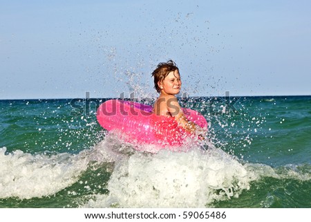 happy boy in a swim ring has fun in the ocean with waves