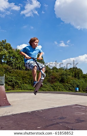 young boy going airborne with his scooter at the skate park
