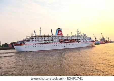 HAMBURG, GERMANY - 25 AUGUST: the famous cruise liner Deutschland with the film crew of the TV series Loveboat leaves the harbor in sunset for an overseas trip at August 25, 2011 in Hamburg, Germany.