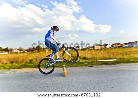 young boy jumping with his dirk bike over a barrier at the street