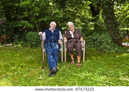 elderly couple sitting hand in hand in their garden