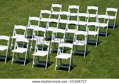 Rows of white empty chairs on a lawn before a wedding or ceremony
