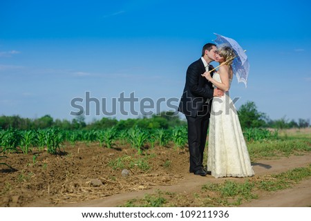 Groom and Bride in wedding dress in a field. Bridal wedding bouquet of flowers