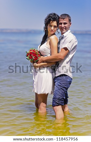 wedding. Sexy bride and casual groom  standing in water. shore. Love story of happy couple. wedding dress and umbrella. Bridal wedding bouquet of flowers.