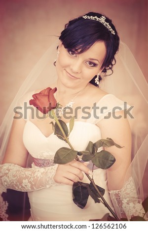 wedding portrait of beautiful smiley bride with red rose. Vintage photo. wedding dress.