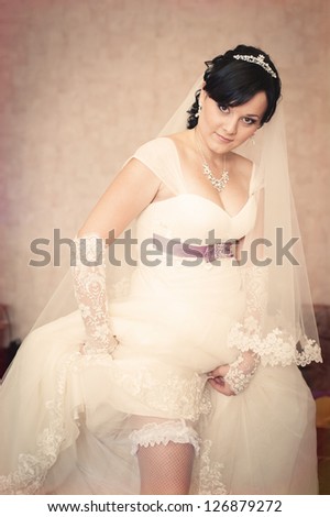 Picture of beautiful female barefoot legs in wedding dress. Bride dresses stockings on feet. Vintage photo