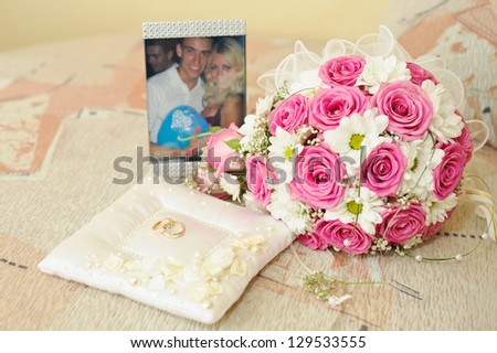 Lovely laughing wedding couple looking through a picture frame. Bridal wedding bouquet of flowers roses. Happy young bride and groom. Wedding couple - new family! golden  rings on a white  pillow.