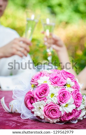 Bridal wedding bouquet of flowers. bride and groom holding beautifully decorated wedding glasses with champaign. Happy young bride and groom outside on their wedding day - Copyspace.