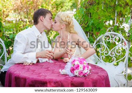 bride and groom holding beautifully decorated wedding glasses with champaign. Happy young bride and groom outside on their wedding day - Copyspace. wedding dress. Bridal wedding bouquet of flowers