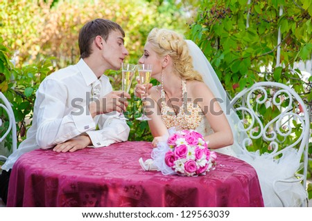 bride and groom holding beautifully decorated wedding glasses with champaign. Happy young bride and groom outside on their wedding day - Copyspace. wedding dress. Bridal wedding bouquet of flowers