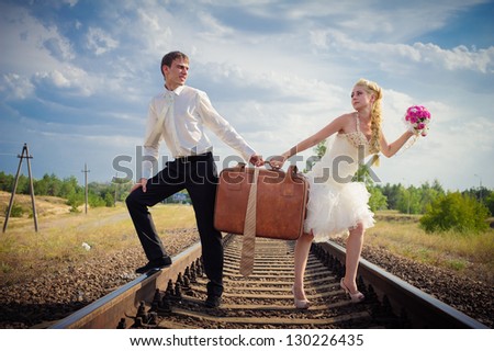 groom embraces the bride on rails. Happy young bride and groom on their wedding day. Wedding couple - new family! wedding dress. Bridal wedding bouquet of flowers