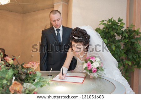 Wedding ceremony. Registry office. A newly-married couple signs the marriage document.Young couple signing wedding documents.