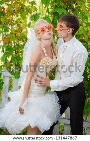 Beautiful bride and groom posing with sunglasses in her wedding day. Close-up of a newlyweds with sunglasses. Happy young bride and groom outside on their wedding day. Bridal bouquet of flowers