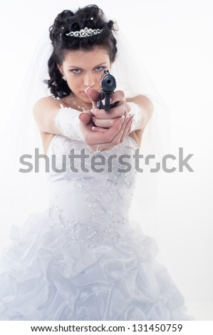 Young woman in a wedding dress with gun on a white background.A bride holding a gun pointing it at the camera. wedding. studio.