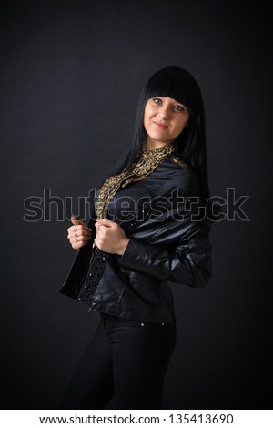 beautiful long-haired girl on a black background. beautiful young woman wearing leather jacket looking at camera.