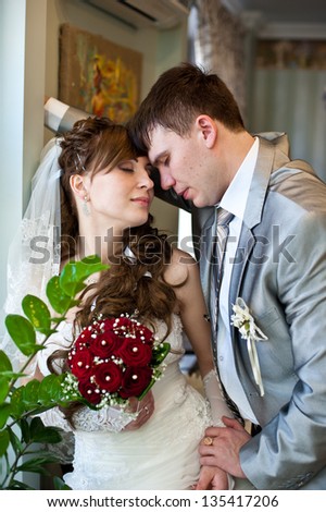 Bride and groom near the window. Bride and groom are standing against the window. portrait of newlywed couples of groom and bride in wedding suit. Married. Newlyweds stand beside window