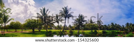 Lake in green tropical forest. tropical park - travel background. Golf Course in Tropical Paradise. Summertime holyday in Dominican Republic, Caribbean. Golf Course on Green Ocean Shore. Luxury Resort