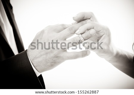 Hands with rings Groom putting golden ring on bride's finger during wedding ceremony Loving couple closeup in studio isolated portrait on white background