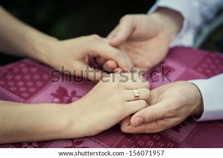 Closeup of a man holding his girlfriend\'s hand at the restaurant. Romantic Couple Holding Each Other\'s Hand At Dinner In An Restaurant. man\'s and woman\'s hands on the table in cafe.