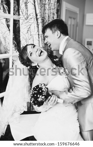 Cute married couple in cafe, groom kissing a bride. Pure tenderness. Bride and groom drinking coffee at an outdoor cafe. a romantic rest in vintage cafe interior. Bridal wedding bouquet of flowers.