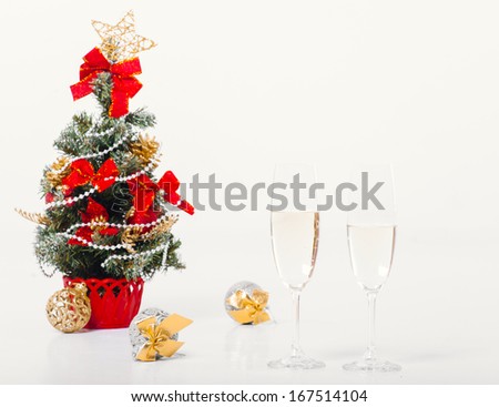 2014 New Year and Christmas Celebration. Two Champagne Glasses and Gifts over white Holiday Background. Glasses of champagne and Christmas decorations in front of Christmas tree for the holidays