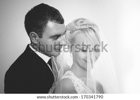 newlyweds embracing and kissing. Cute young married couple posing on white background. Bridal happy couple isolated on white background.  Bouquet of flowers, wedding dress