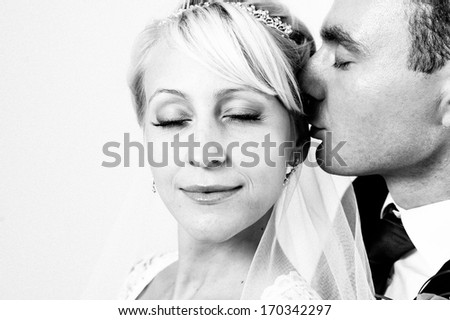 newlyweds embracing and kissing. Cute young married couple posing on white background. Bridal happy couple isolated on white background.  Bouquet of flowers, wedding dress