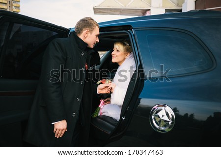 Bride and groom inside a classic car. They are happy. Bride and groom kissing in limousine on wedding-day.