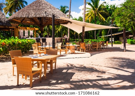 Luxury beach resort on Caribbean sea in Dominican Republic, cozy cafe on white sandy coast, beautiful big palm trees, enjoying day spa, summer holidays concept