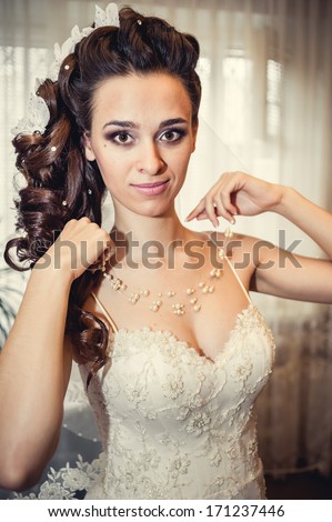 Bride dressing gown. bride preparing for a wedding. bride is getting dressed in the room. brunette young bride prepare for the event by makeup artist.