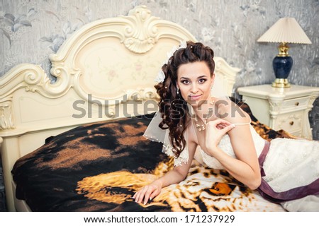 Portrait beautiful bride on bed in wedding day. morning bride. Beautiful bride in white wedding dress lying on the bed in her bedroom.