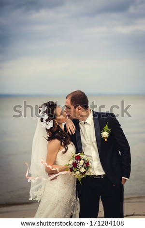A wedding by the sea. Honeymoon. The bride and groom hugging on the shore of Lake. groom and bride hugging on a green lake. Groom and Bride in a park. wedding dress. Bridal wedding bouquet of flowers